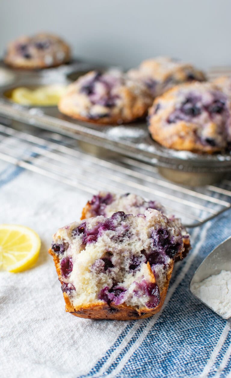 A pan of Lemon blueberry muffins, with one cut open in the foreground.