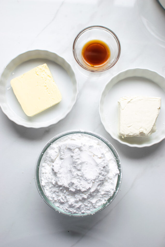 Ingredients for cream cheese frosting including butter, cream cheese, vanilla and confectioners sugar.