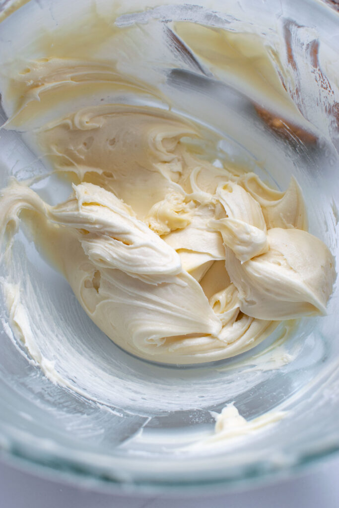 Cream cheese frosting in a glass mixing bowl.