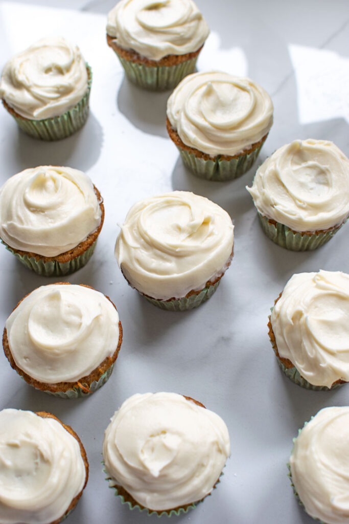 Cream cheese frosting swirled on to carrot cupcakes with a spoon.