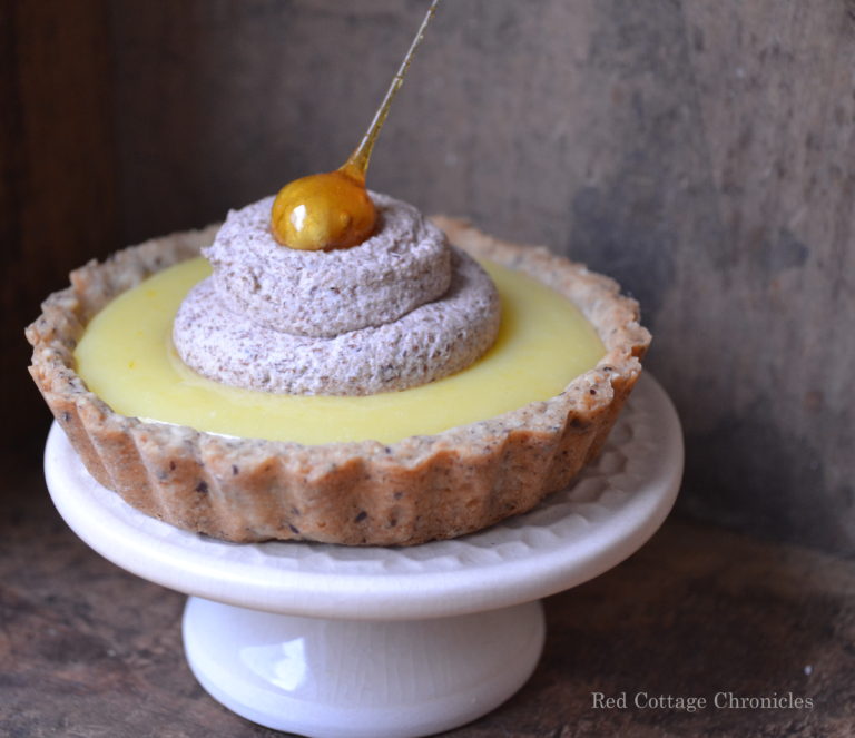 A tart filled with orange cream inside a hazelnut crust and topped with chocolate mousse.