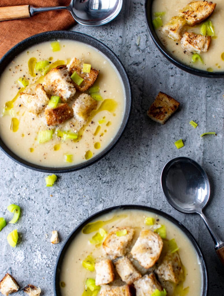 Overhead view of potato leek soup topped with croutons and olive oil.