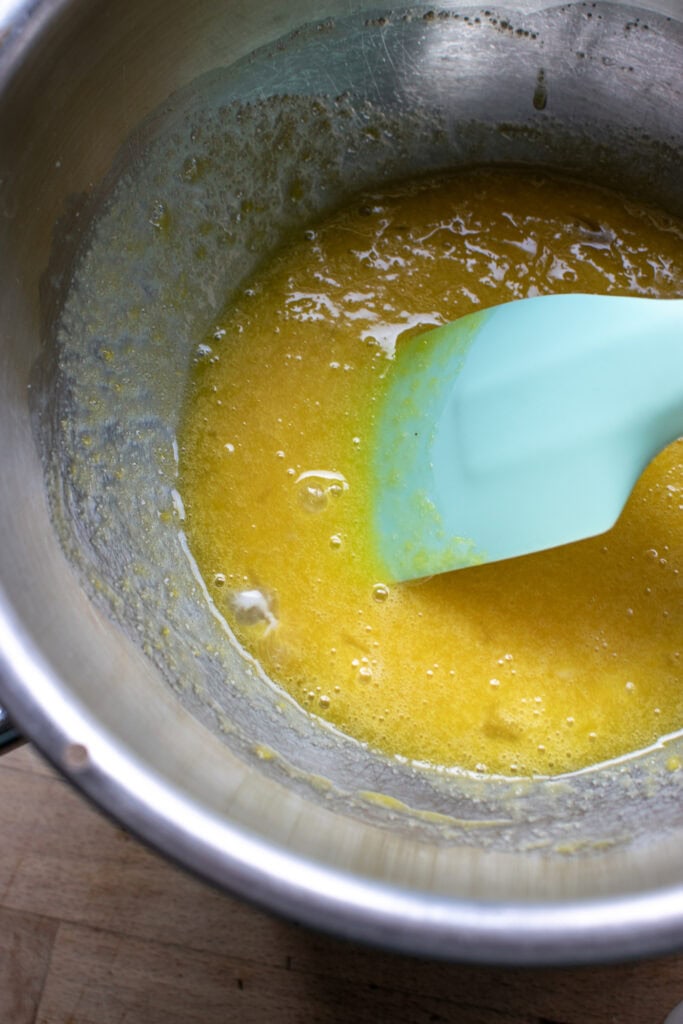 Sugar, egg yolks and whole egg heating in a double boiler.