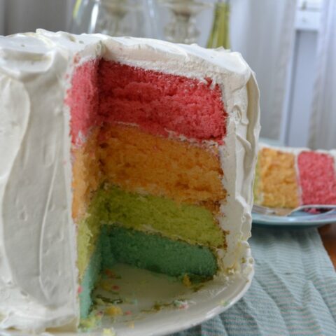 A 4 layer cake with pink, orange, green and blue layers.