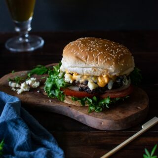 Burger with Buffalo Wing Sauce and Blue Cheese on a cutting board.