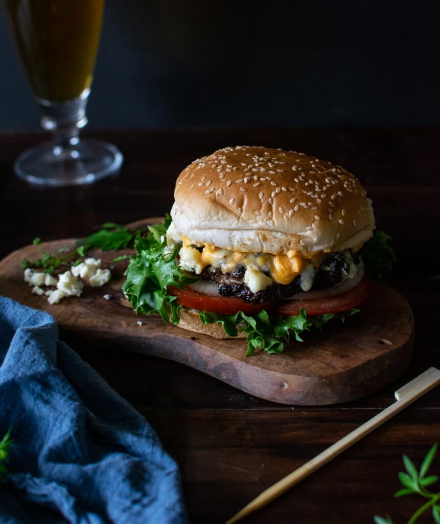 Burger with Buffalo Wing Sauce and Blue Cheese on a cutting board.