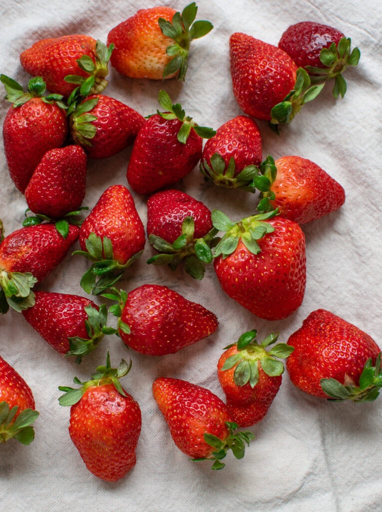 Freshly washed strawberries drying on a kitchen towel.