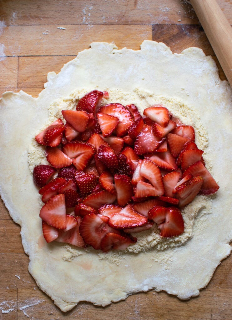 Strawberry filling on top of rolled out pie dough that has been sprinkled with ground almonds.