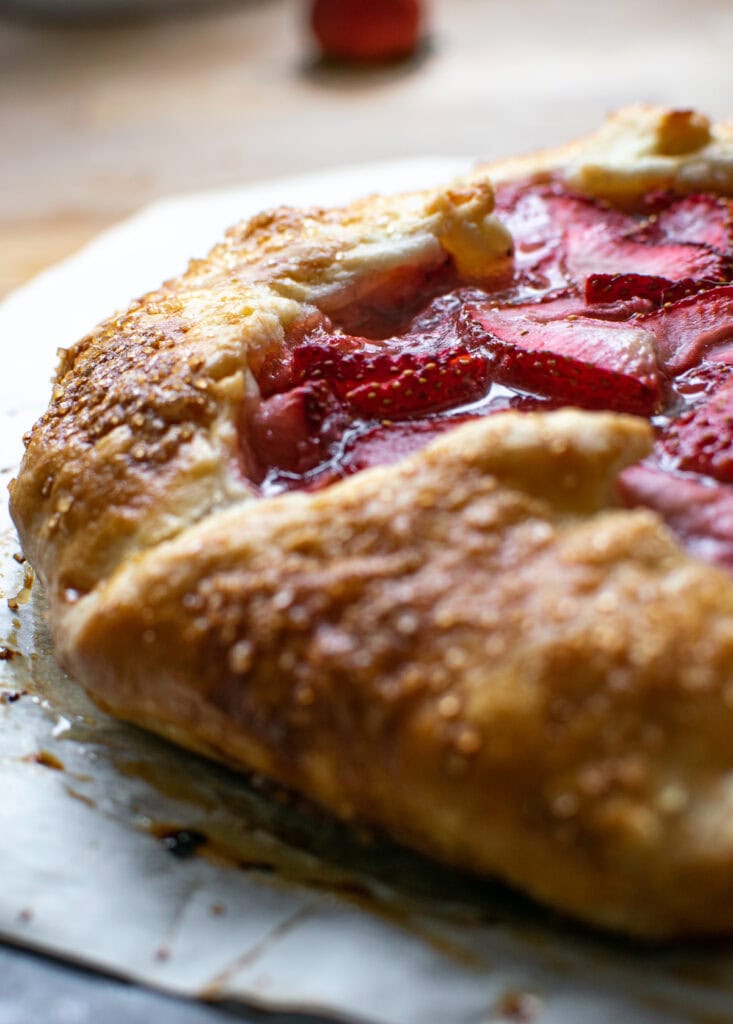 A close up of the golden crust and bubbly filling of a strawberry galette