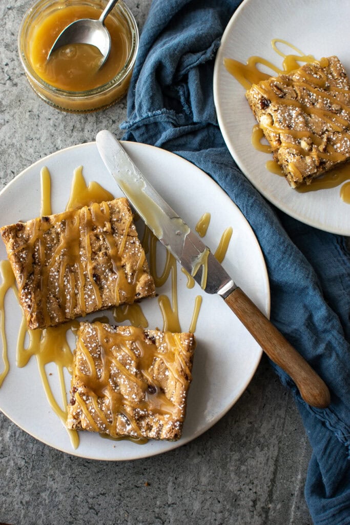 Blondie bars drizzled with caramel sauce on a dessert plate.