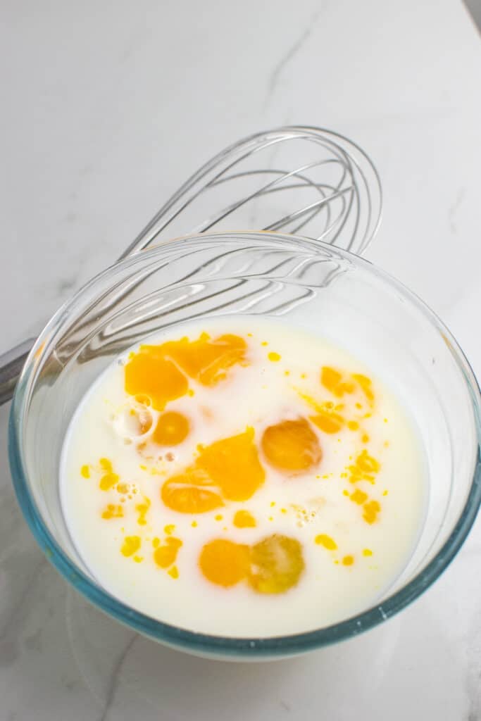 Eggs, milk and vanilla in a clear glass bowl