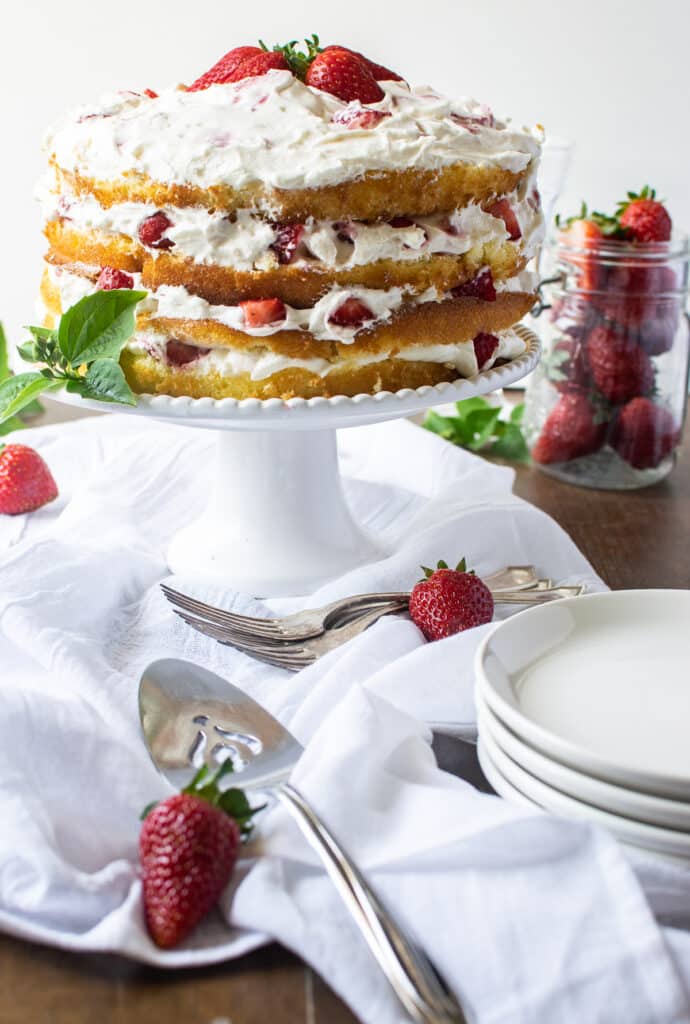 4 layer vanilla strawberry cake on a cake stand.
