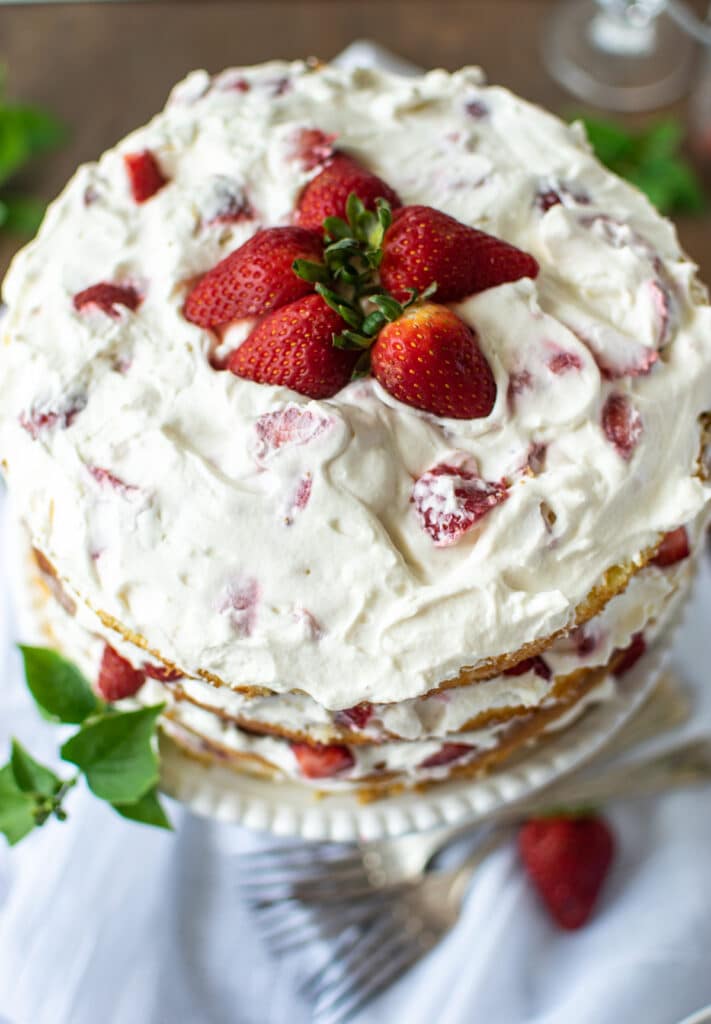 Overhead view of a 4 layer strawberry and cream cake topped with fresh strawberries.