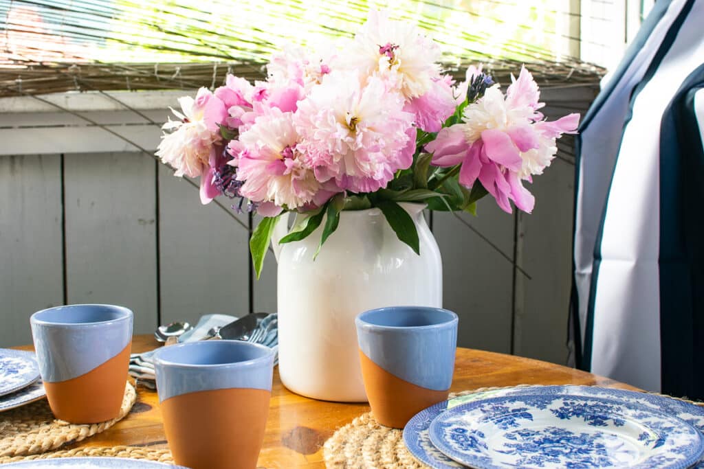 A white tin pitcher filled with pink peonies.