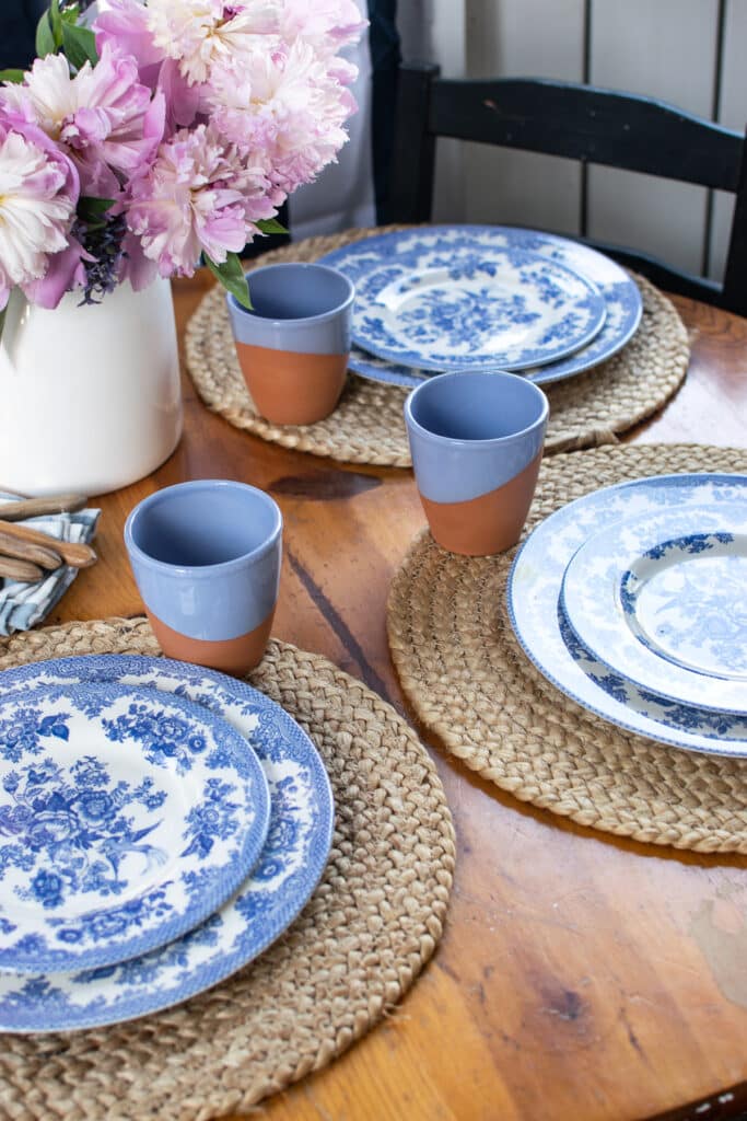 A round table set with blue and white plates and blue and terra cottage glasses.