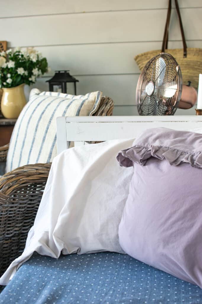 Pillows propped up on a bench covered in pink and purple pillow cases with ruffles.