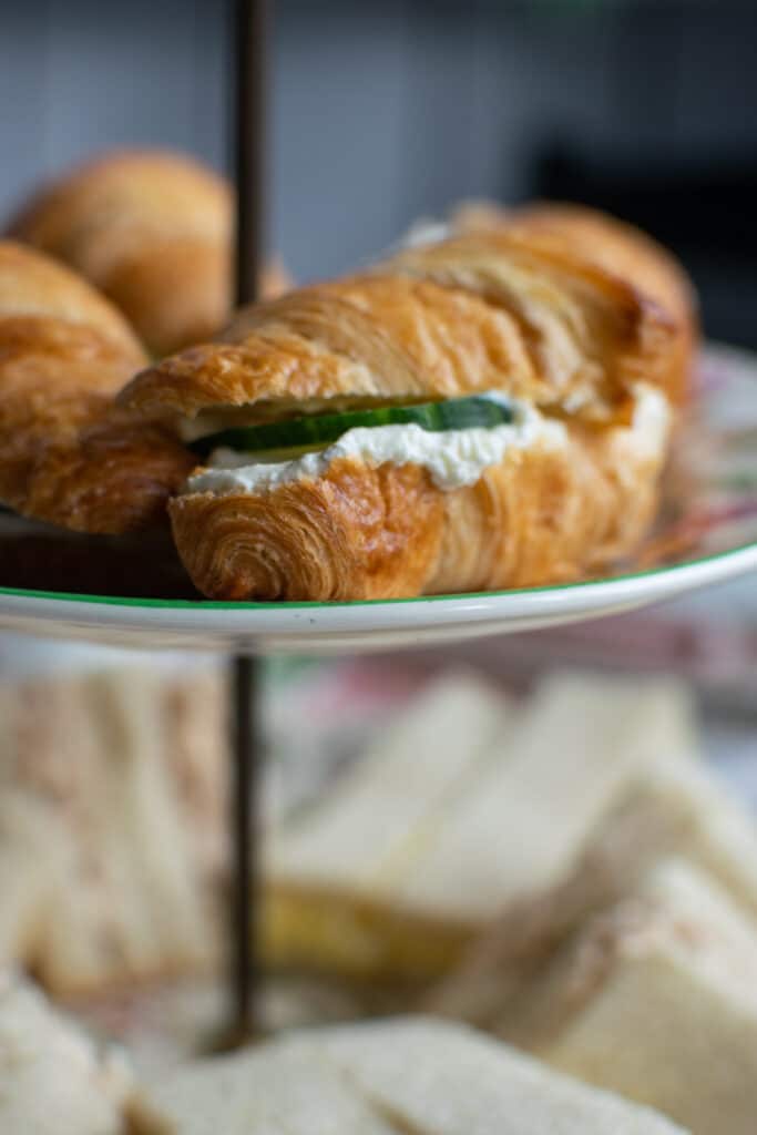 A close up of mini croissants with whipped cream cheese and cucumber for an afternoon tea party idea.