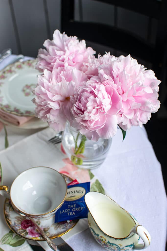 A clear vase filled with fresh cut pink peonies in full bloom.