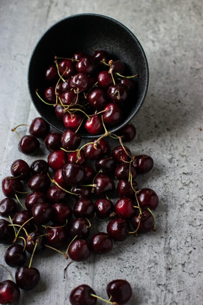 A bowl tipped out with fresh cherries flowing out onto the counter.