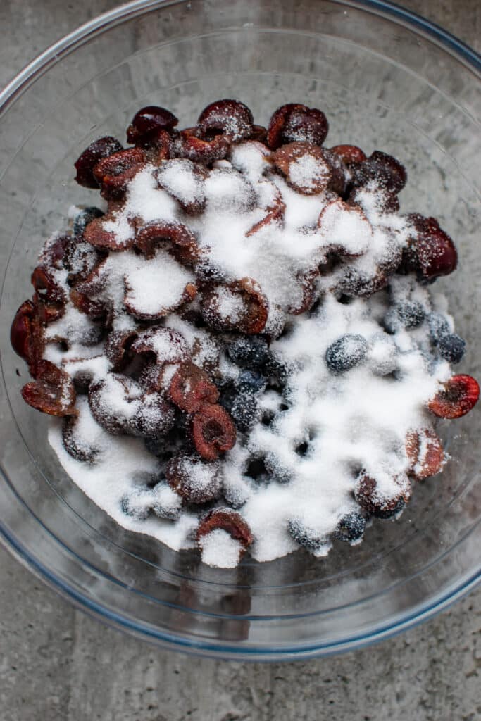 A bowl of fresh cherries and blueberries sprinkled with sugar.