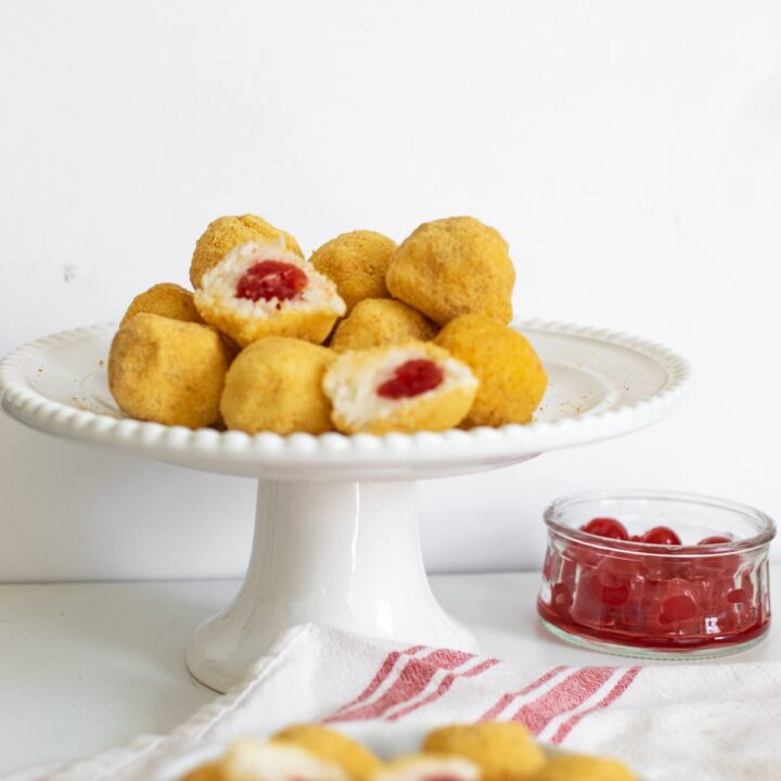 A plate of cherry surprise cookies with some cut in half to expose the cherry in the middle.