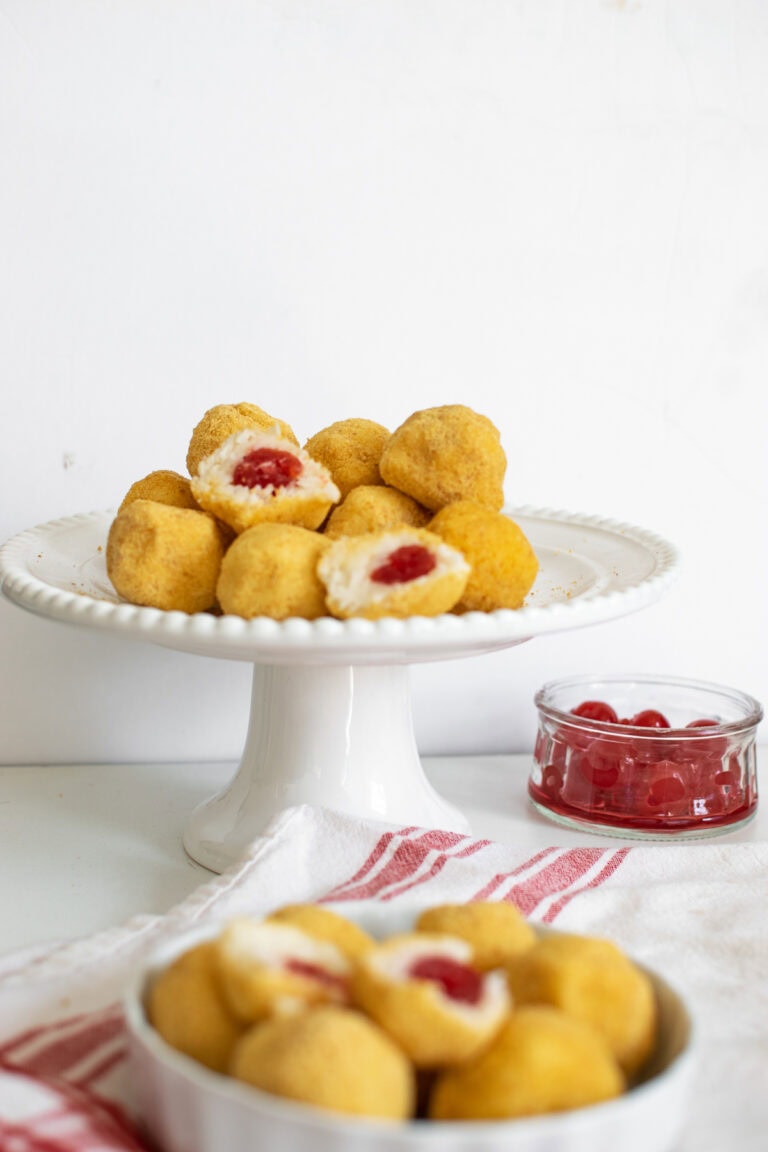 A plate of cherry surprise cookies with some cut in half to expose the cherry in the middle.