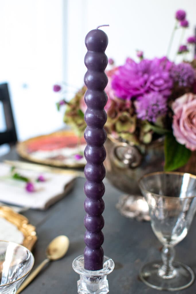 A purple candle that looks like little round balls on top of one another, and is about 9 inches tall.