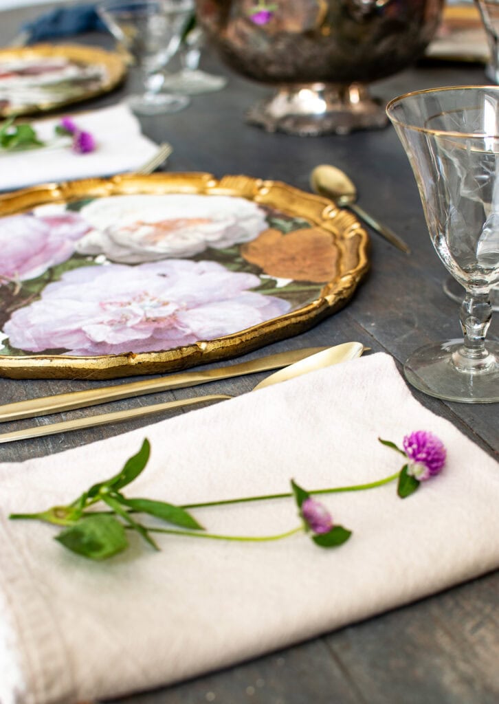 Autumn tablescape ideas using purple flowers and brightly coloured floral charger plates with gold edges.