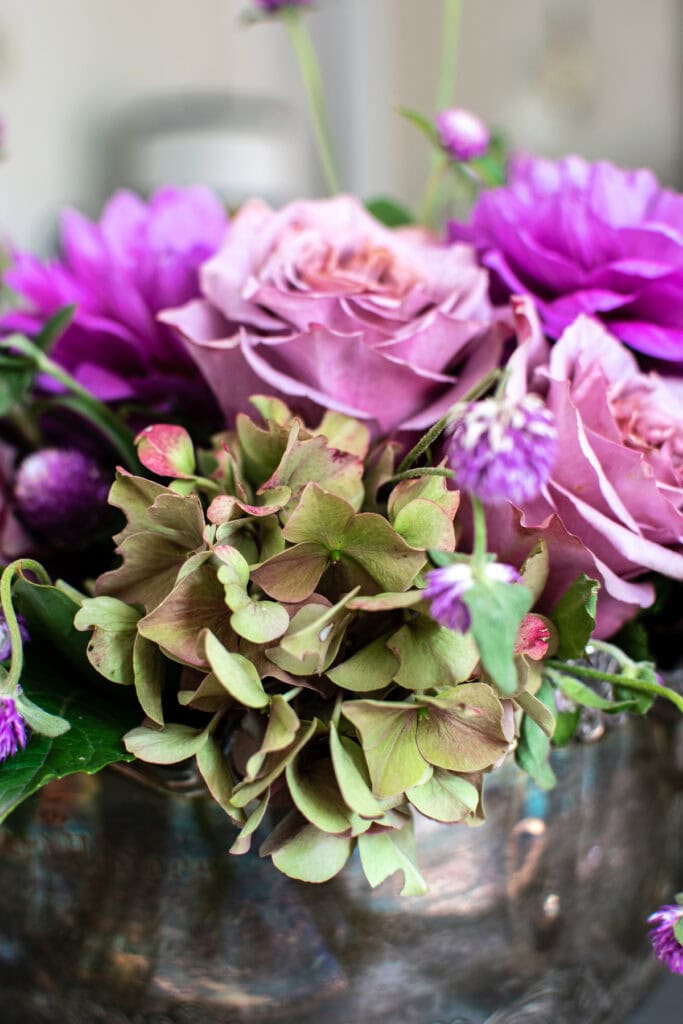 Floral centrepiece with green and plum hydrangea, mauve roses and purple dahlias