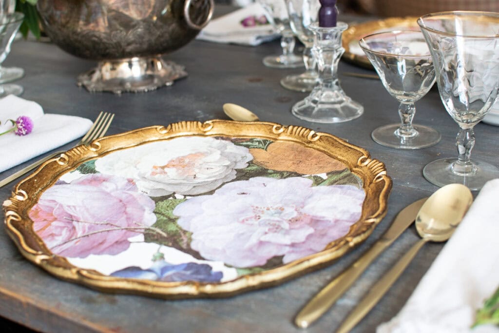 A floral patterned charger plate with pink, purple and cream rose pattern.