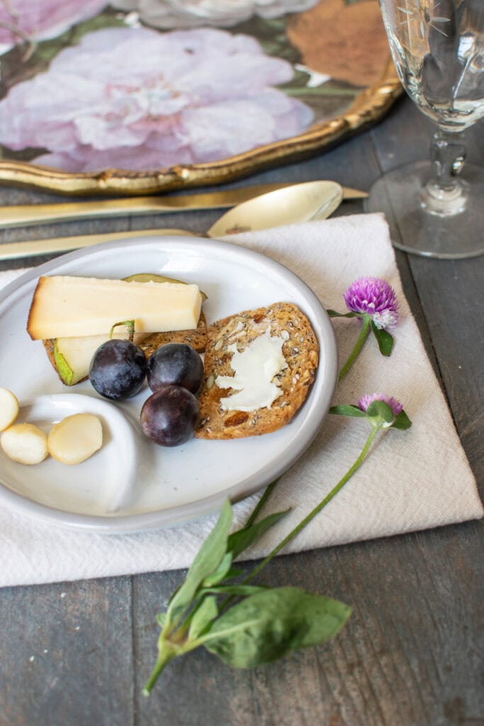 A small appetizer plate with crackers, cheese, grapes and nuts.