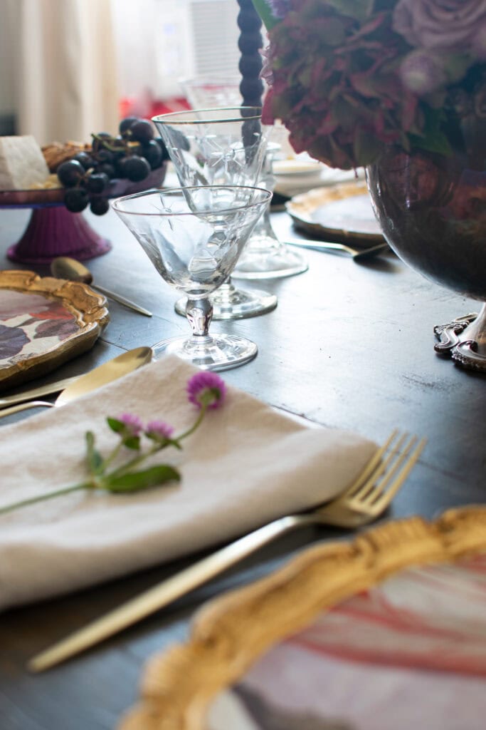 A view across a table set for an autumn dinner with light filtering through the crystal glasses.