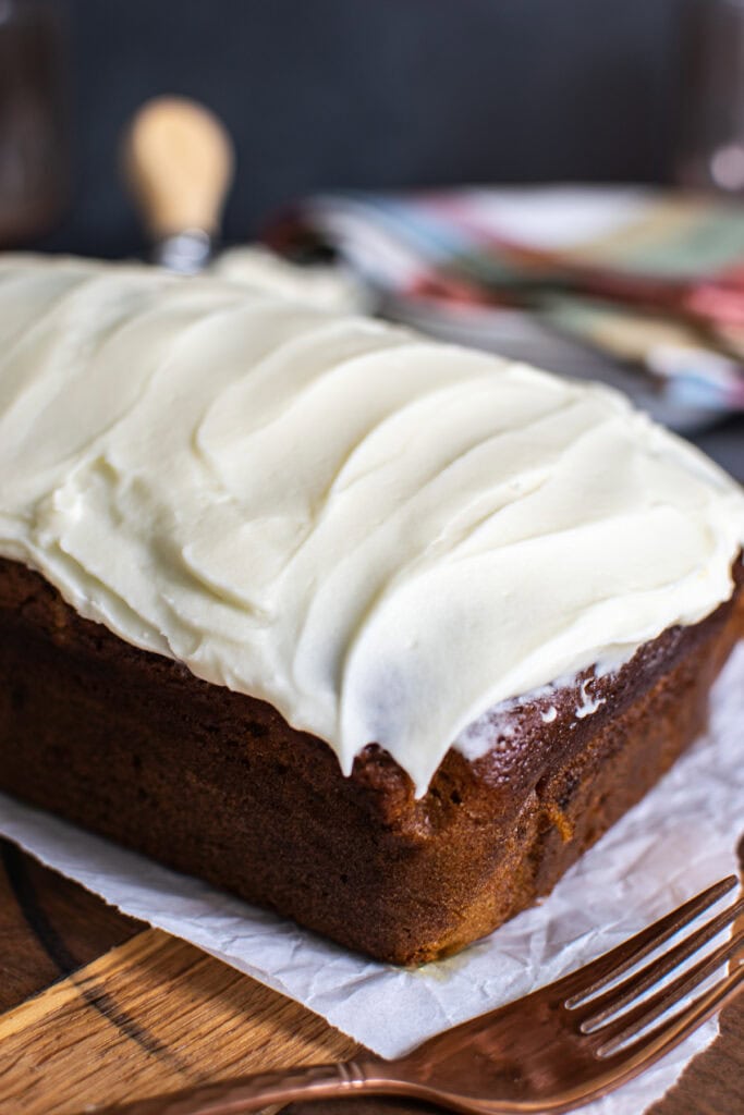 A loaf of pumpkin bread frosted with cream cheese frosting.