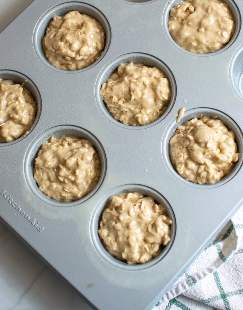 An overhead view of maple cinnamon oatmeal muffin batter in muffin tins.