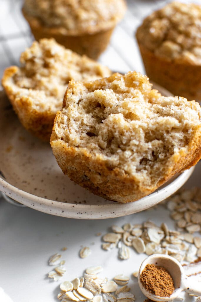 An oatmeal muffin torn in half sitting a plate.