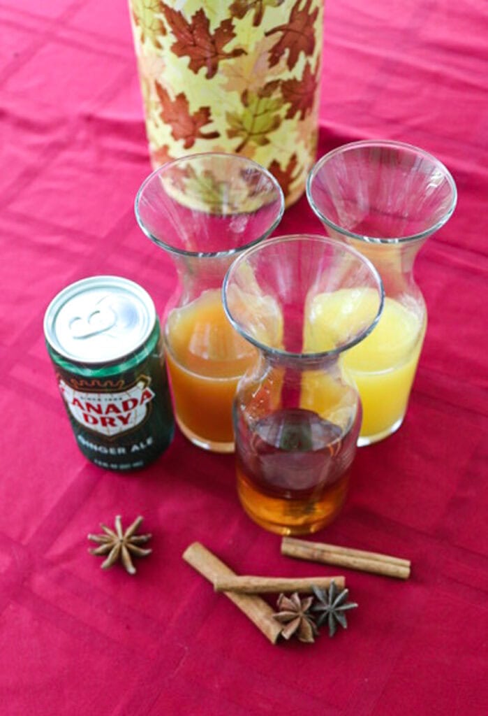 Ingredients to make an apple cider and spiced rum cocktail including gingerly, spiced rum, and apple cider.