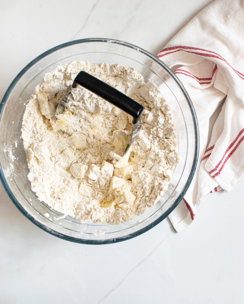 A photo of how make pie pastry but cutting butter into the flour with a pastry cutter.