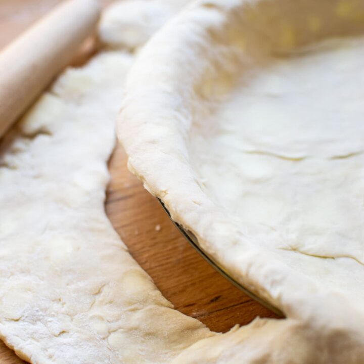 One side of a pie plate with pie pastry trimmed to fit.