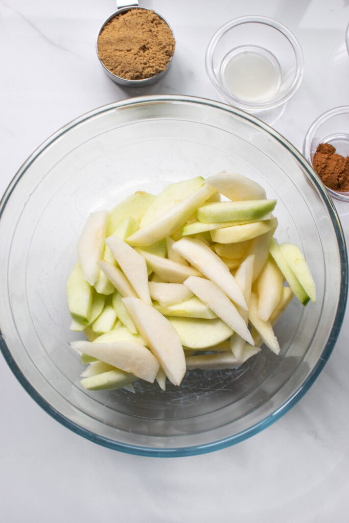 Sliced apples and pears in a glass bowl.