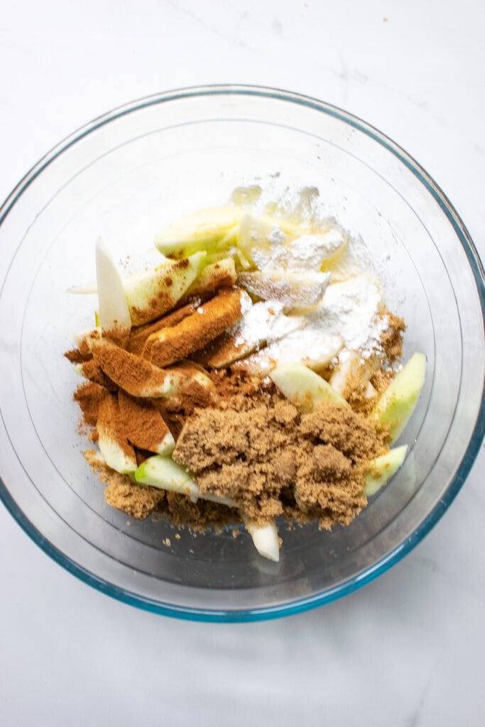 Sliced apples and pears topped with spices and brown sugar before mixing together to make an galette filling