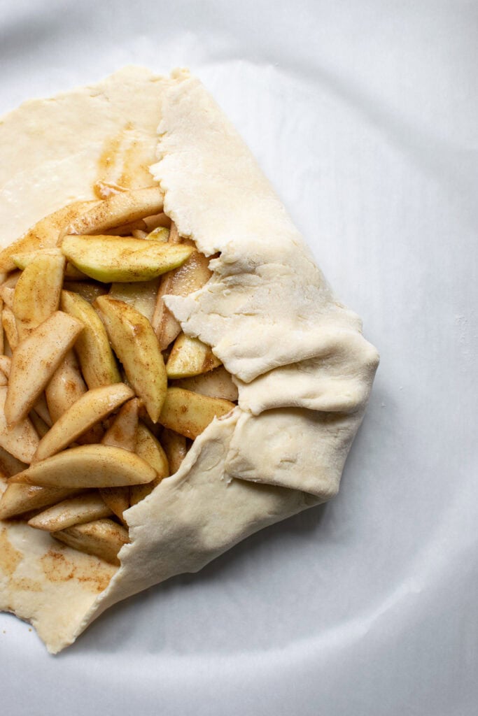 Over head view of how to fold in edges of pastry dough to make a galette.