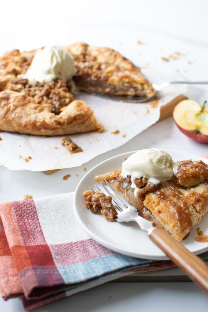 An apple galette with a slice on a plate topped with ice cream.