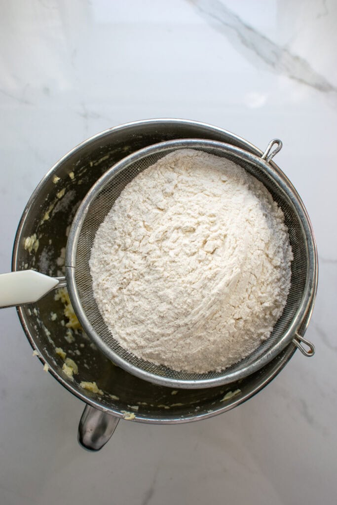 Flour being sifted into a mixing bowl to make sweet pastry dough.