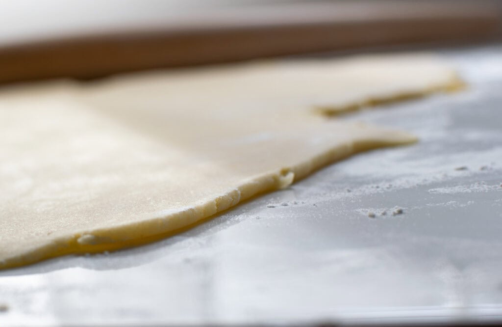 Pastry rolled out on a marble counter to show how thick it should be rolled.