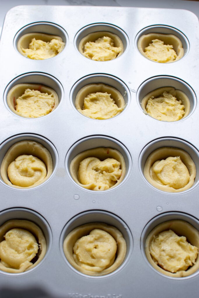 Frangipane batter in tart shells before being baked into Cherry Bakewell tarts.