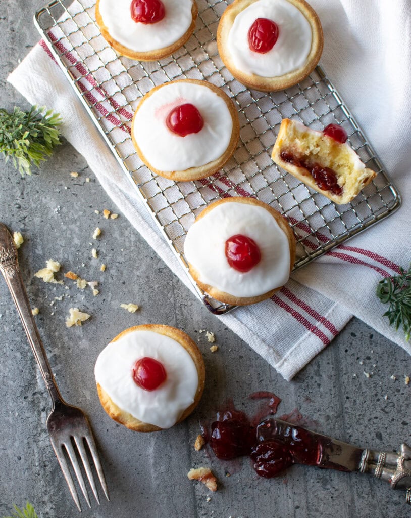 Overhead view of 3 and a half cherry Bakewell tarts.  The half one is on its side to show the filling.