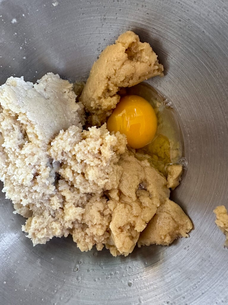 Eggs added to a mixture of butter and brown sugar to make Oatmeal cookies.