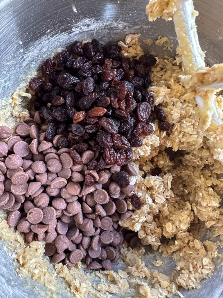 Oatmeal cookie dough with raisins and chocolate chips on top, waiting to be mixed in.