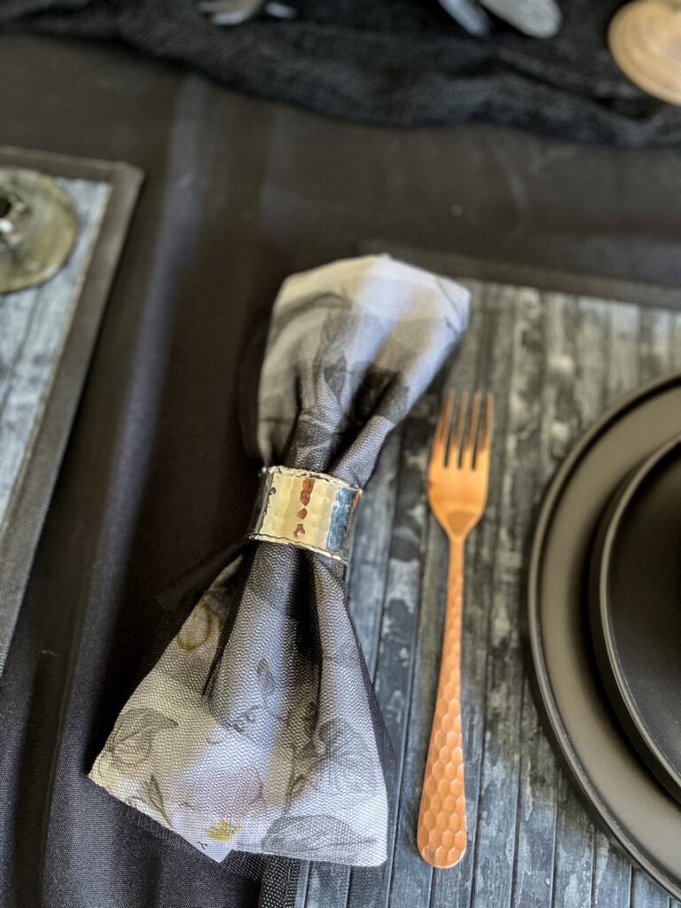 A dinner napkin wrapped in black tulle with a silver napkin ring.