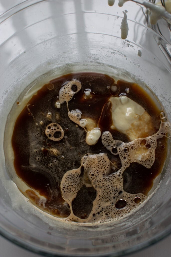 Coffee and vegetable oil added to a sugar/egg mixture in a glass mixing bowl.